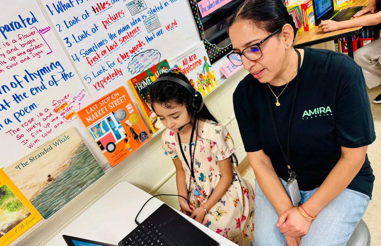An Amira educator supporting a student wearing a headset at a laptop